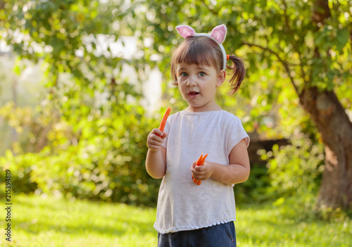 Happy little girl eating fresh and sweet carrot.
