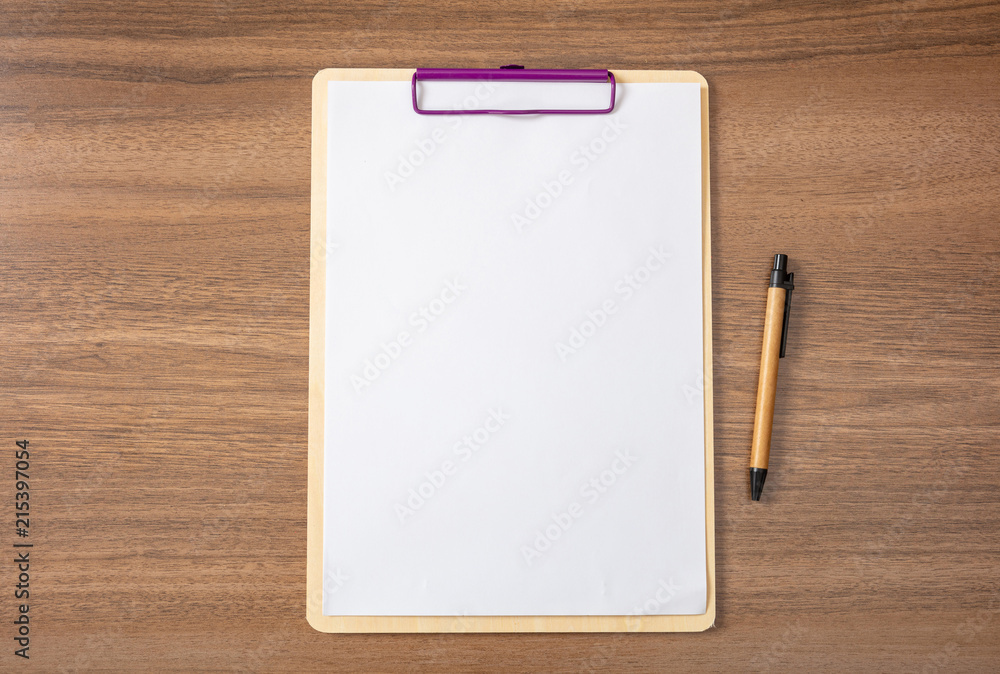 Clipboard with blank paper sheet and a pen on wooden desk, space for tex Clipboard with blank paper sheet and a pen on wooden desk, space for tex