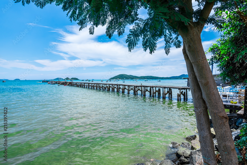 View of old wooden jetty along with the sea from the point under tree at Sattahip, Chonburi province, Thailand  