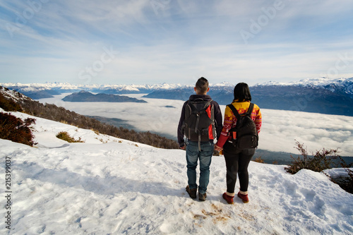 Couple holding hands standing on a high snowy mountain looking the landscape in Patagonia Argentina photo