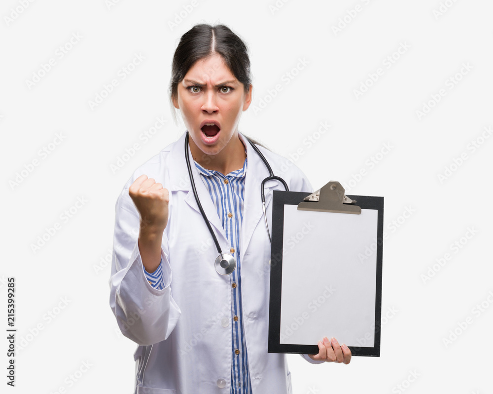 Young hispanic doctor woman holding clipboard annoyed and frustrated shouting with anger, crazy and yelling with raised hand, anger concept Young hispanic doctor woman holding clipboard annoyed and frustrated shouting with anger, crazy and yelling with raised hand, anger concept