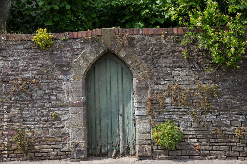 Green door in a stone wall in the stunning little village of Usk in South Wales