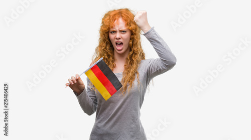 Young redhead woman holding flag of Germany annoyed and frustrated shouting with anger, crazy and yelling with raised hand, anger concept