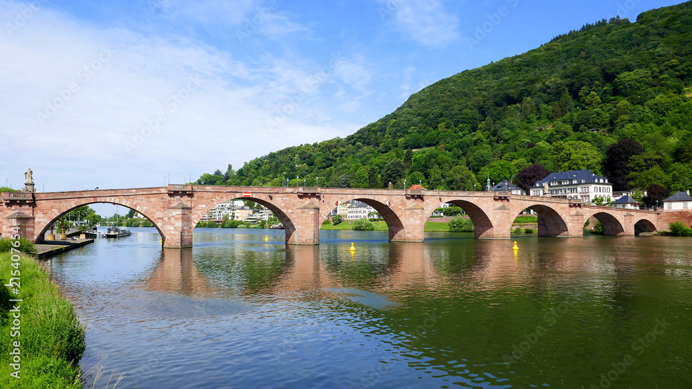 alte Heidelberger Brücke mit angrenzendem Odenwald spiegelt sich im Neckar bei Sonne