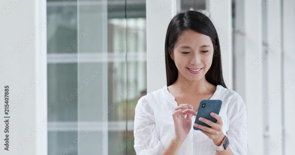 Woman sending sms on cellphone inside building Woman sending sms on cellphone inside building