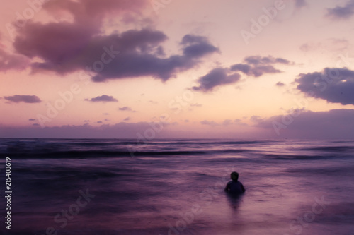 A lonely young man in the sea during the sunset , looking at the bloody cloud,thinking of his memories © Akamal