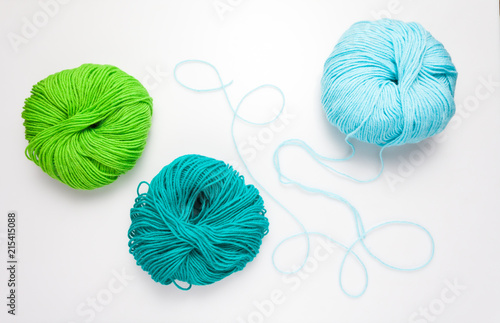 top view of colored yarn balls and knitting needles on white