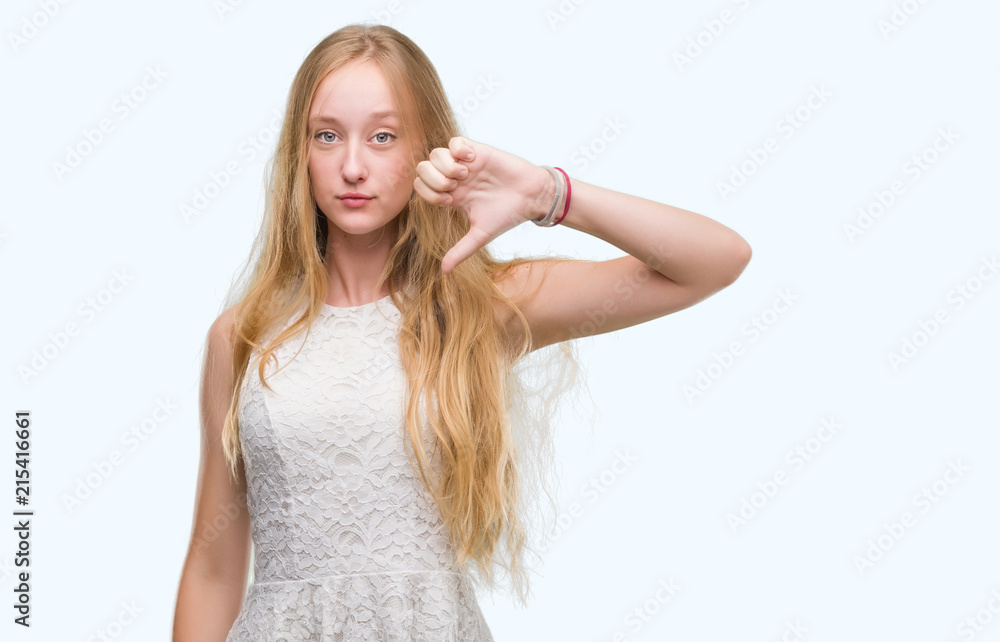 Blonde teenager woman with angry face, negative sign showing dislike with thumbs down, rejection concept Blonde teenager woman with angry face, negative sign showing dislike with thumbs down, rejection concept