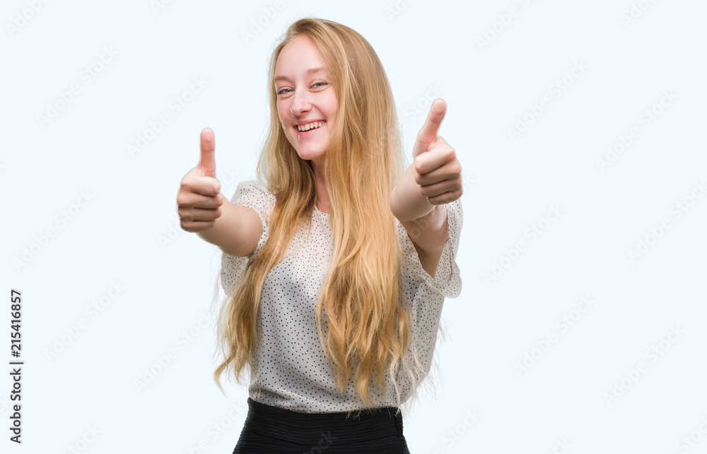 Blonde teenager woman wearing moles shirt approving doing positive gesture with hand, thumbs up smiling and happy for success. Looking at the camera, winner gesture. Blonde teenager woman wearing moles shirt approving doing positive gesture with hand, thumbs up smiling and happy for success. Looking at the camera, winner gesture.