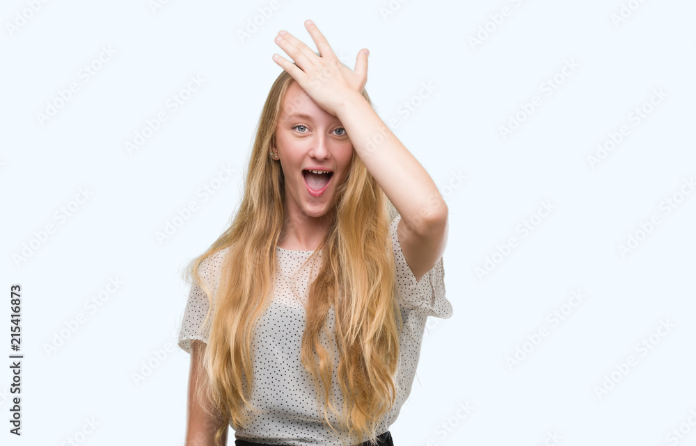 Blonde teenager woman wearing moles shirt surprised with hand on head for mistake, remember error. Forgot, bad memory concept.