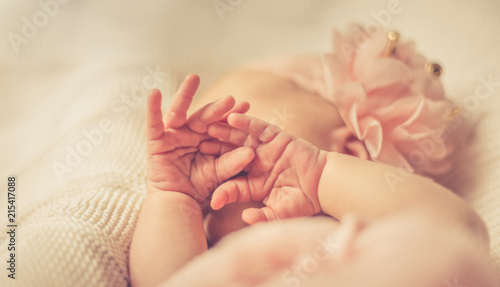 Newborn baby girl's hands covering her sleeping face. Selective focus. Close up