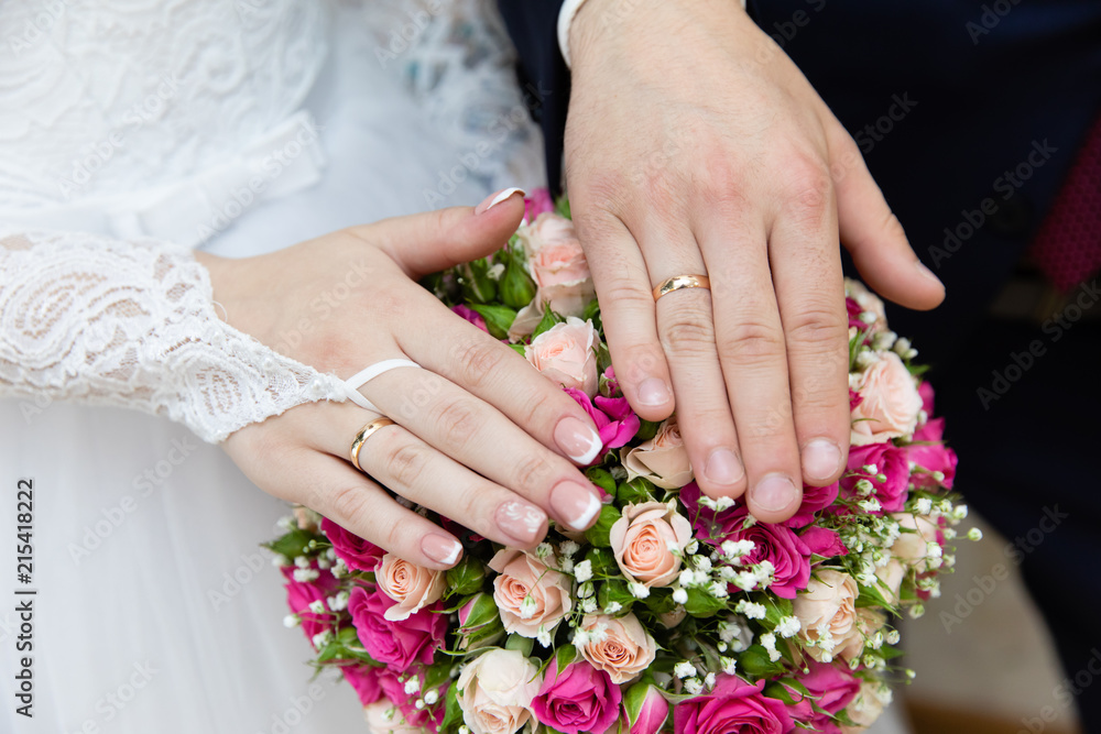 Hands of the groom and bride with rings and bridal bouquet Hands of the groom and bride with rings and bridal bouquet