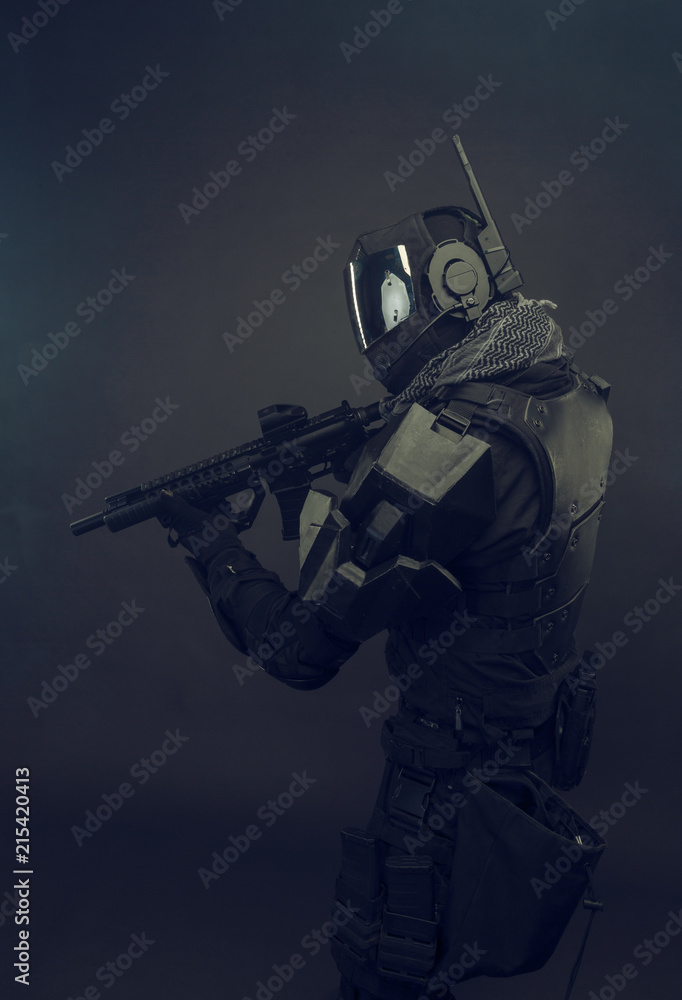 Cosplay futuristic solder with gun. Dark background.