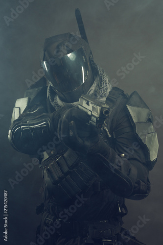 Cosplay futuristic solder with handgun. Dark background, hazy air.