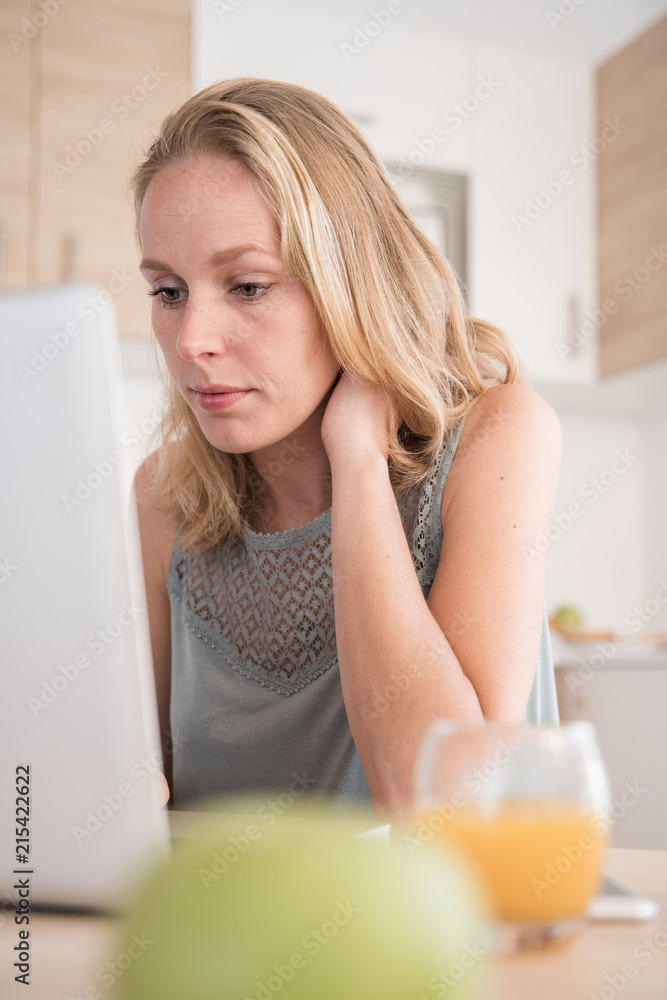 Woman sitting at a table leaning towards a laptop Woman sitting at a table leaning towards a laptop