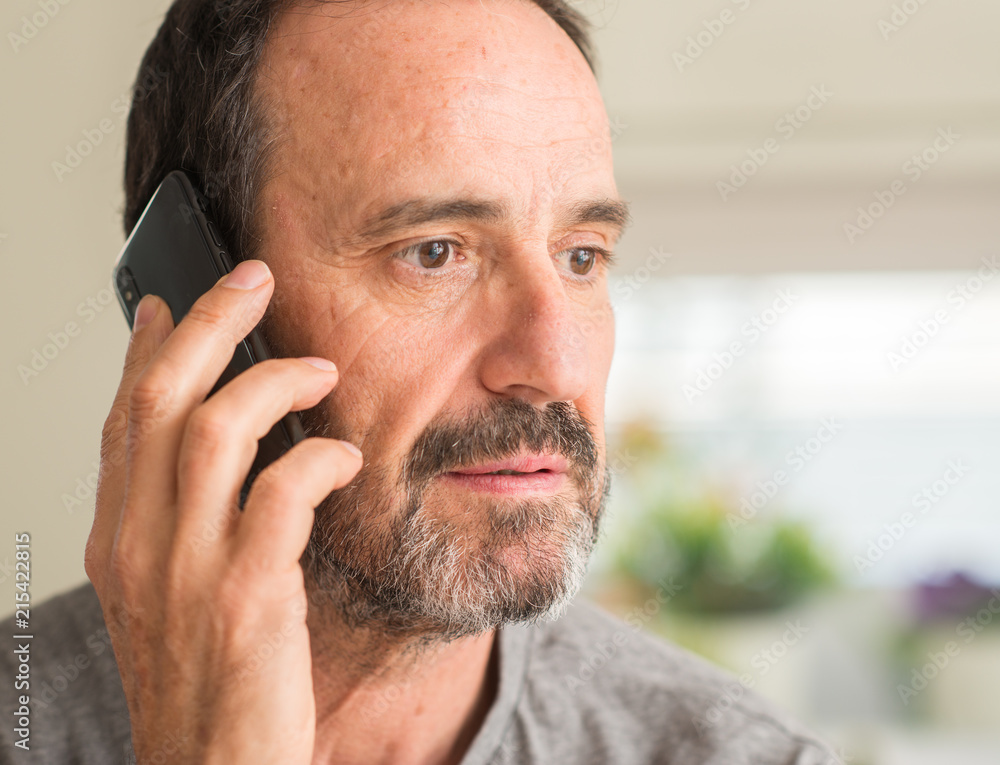 Middle age man using smartphone with a confident expression on smart face thinking serious Middle age man using smartphone with a confident expression on smart face thinking serious