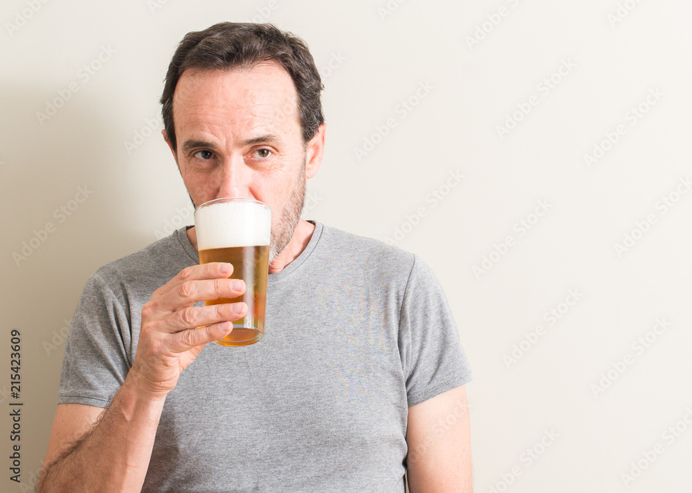 Senior man drinking beer with a confident expression on smart face thinking serious