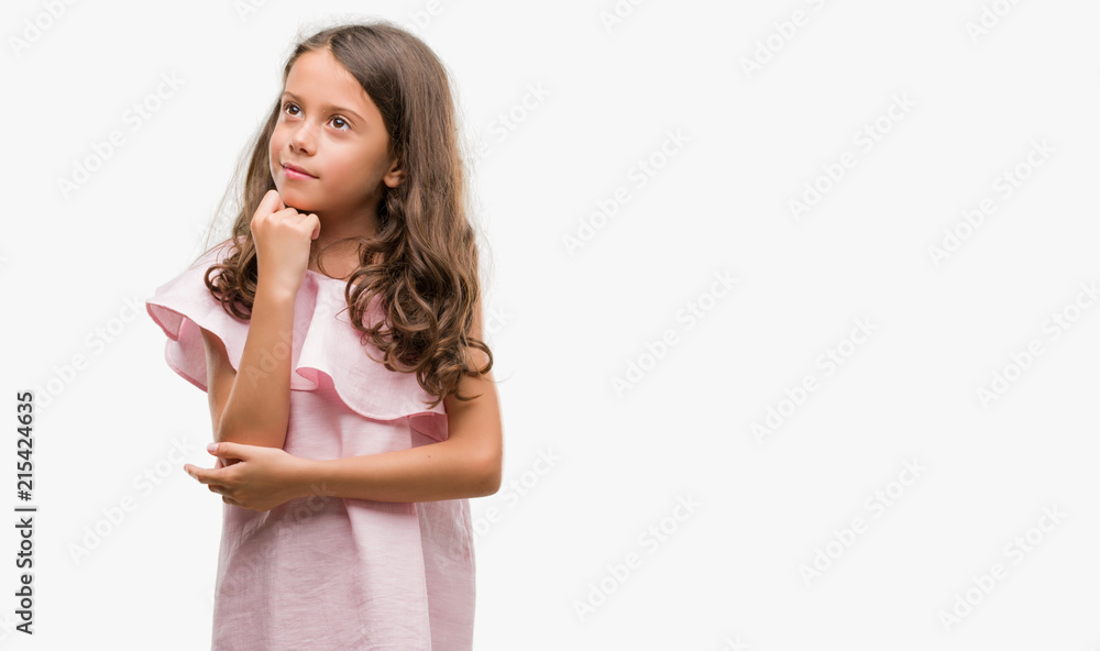 Brunette hispanic girl wearing pink dress with hand on chin thinking about question, pensive expression. Smiling with thoughtful face. Doubt concept. Brunette hispanic girl wearing pink dress with hand on chin thinking about question, pensive expression. Smiling with thoughtful face. Doubt concept.