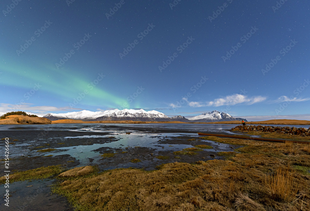 Winter lake near mountain in Hofn, Iceland. Northern lights and blue sky background.