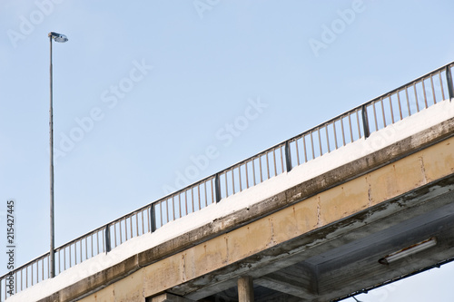 Bridge with railing and street light against blue sky.