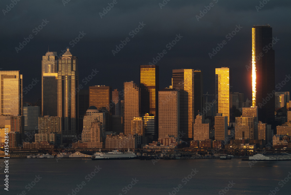 Obraz premium Dramatic Seattle, Washington Sunset Over Elliott Bay. Just after a rain squall the setting sun emerges to light up the skyscrapers along the Seattle waterfront.