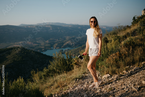 Cute girl enjoying on the sandy road with canyon and emerald lake on the background on the sunset in Spain. Traveler in the mountains.