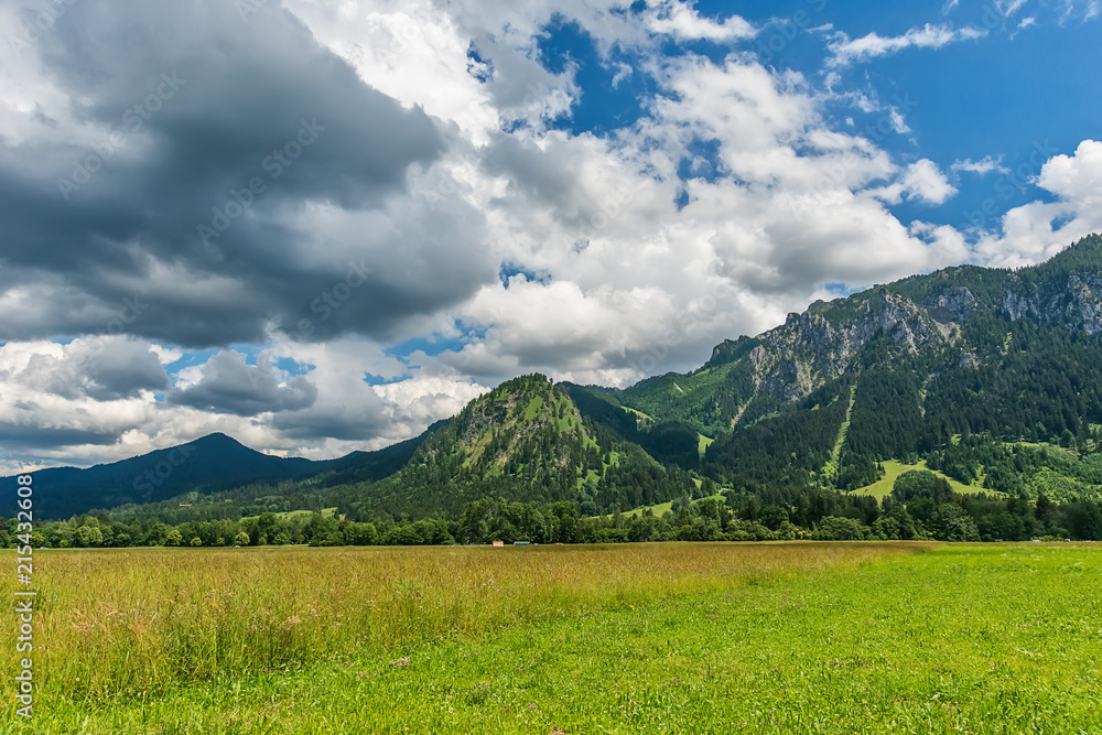 Naklejka premium Idyllic landscape in the Alps with green meadows and clouds