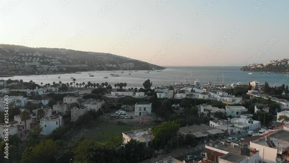 Drone flying between two minarets of local mosque towards the sea in small coastal Aegean town (4K aerial)