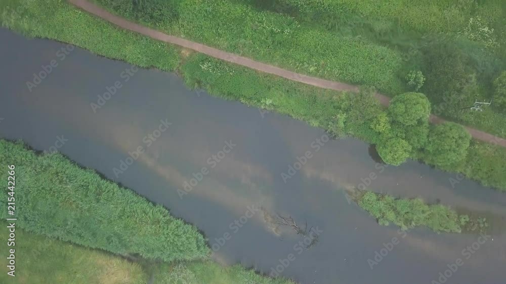 Aerial view crossing over small river with footpath and trees visible Aerial view crossing over small river with footpath and trees visible