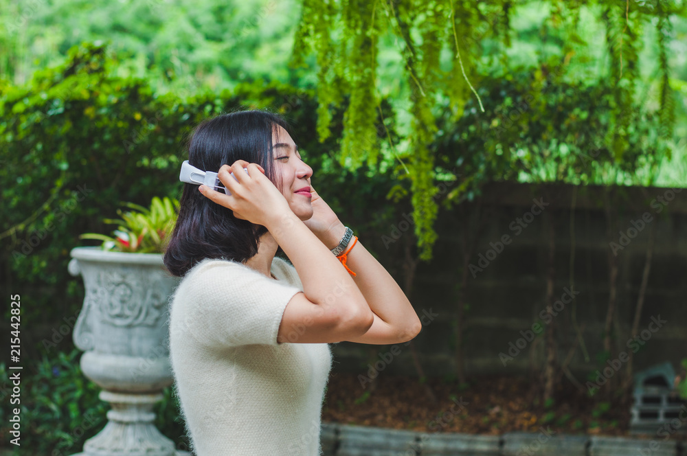 Naklejka premium Beautiful Asian girl listening to music in the garden.