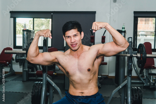 Asian muscular men are lifting weights in the gym.