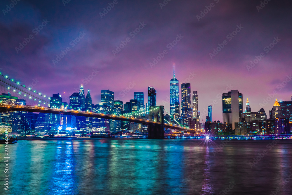 Fototapeta premium Skyline of downtown New York City Brooklyn Bridge and skyscrapers over East River illuminated with lights at dusk after sunset view from Brooklyn