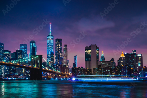 Skyline of downtown New York City Brooklyn Bridge and skyscrapers over East River illuminated with lights at dusk after sunset view from Brooklyn