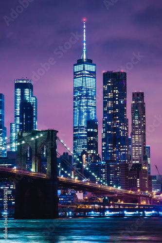 Skyline of downtown New York City Brooklyn Bridge and skyscrapers over East River illuminated with lights at dusk after sunset view from Brooklyn © Happy Stock