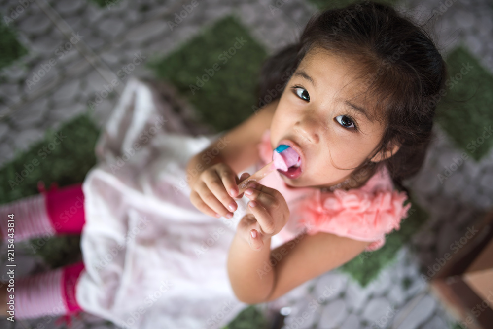 A young girl eating ice cream delicously A young girl eating ice cream delicously