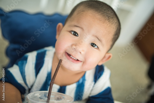 Adorable asian boy smiling during drinking iced drink