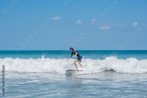 Young man, beginner Surfer learns to surf on a sea foam on the Bali island photo