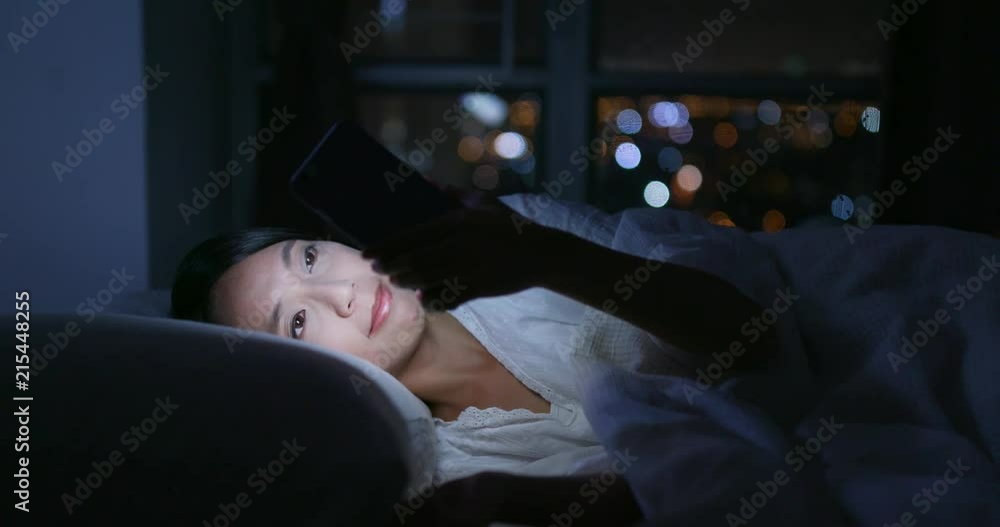 Woman use of mobile phone and lying on bed at night Woman use of mobile phone and lying on bed at night