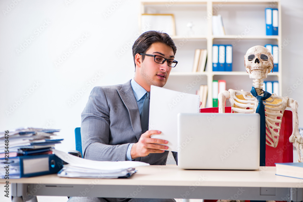 Businessman working with skeleton in office Businessman working with skeleton in office