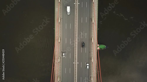 Tour boat goes under the bridge. Cars driving on the bridge.