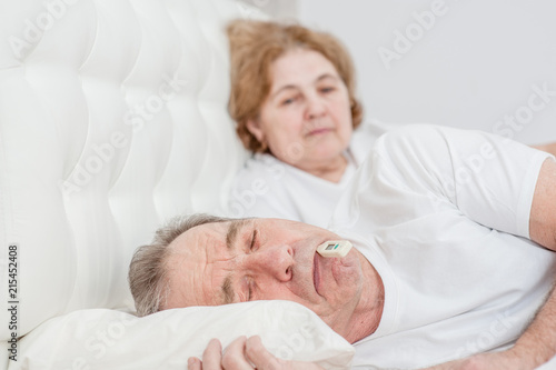 senior woman with sick husband on the bed