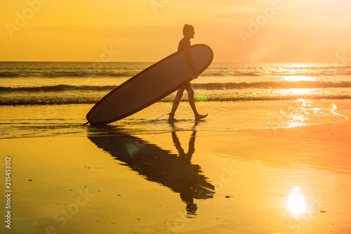 Vacation Silhouette Of A Surfer Carrying His Surf Board Home At Sunset With Copy Space