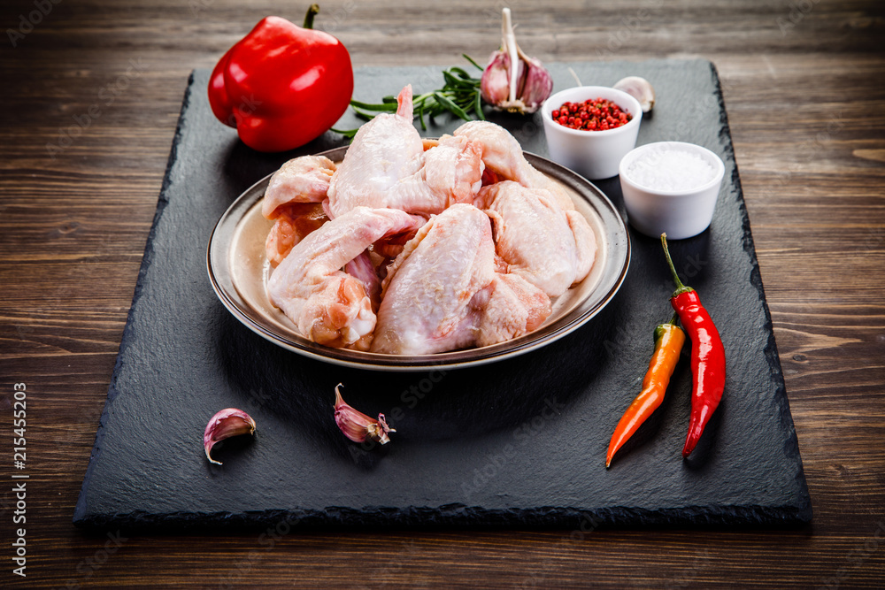 Raw chicken wings on black stone on wooden background