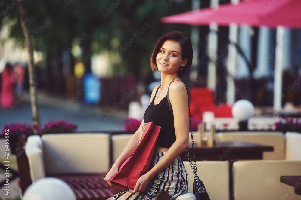 Fototapeta premium Young happy woman with bags in town . Girl resting after a shopping trip