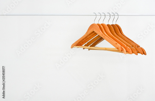 row of empty wooden hanger on a white metal clothes rack on white background, copy space