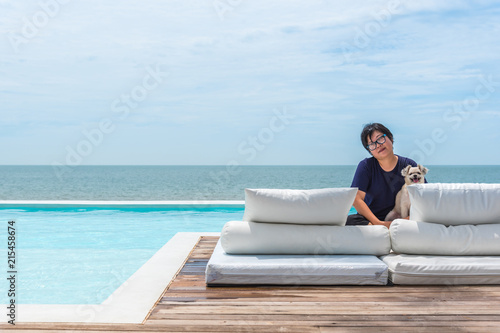 Woman and dog on white bed at pool seaside the sea