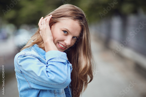 A blonde girl is smiling on a city street. Close-up portrait.