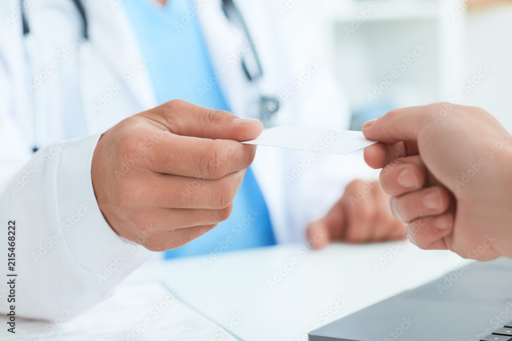 Male doctor's hand give white blank calling card to woman closeup in office. Physical, disease prevention, examine patient, instrument shop, healthy lifestyle, family doctor concept Male doctor's hand give white blank calling card to woman closeup in office. Physical, disease prevention, examine patient, instrument shop, healthy lifestyle, family doctor concept