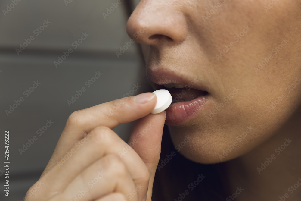 Obraz premium Woman taking a tablet. Close up hand with a pill and the mouth