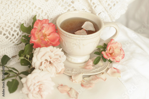 Aromatic tea in a vintage mug and pink roses, a delicious and beautiful breakfast. Pastel shades,